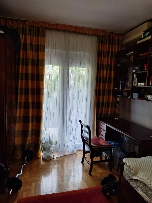 A bright room with a desk, wardrobe, and balcony access.