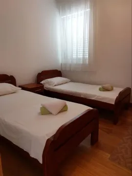 Svijetla spavaća soba sa dva singl kreveta i drvenim podom. - image 10