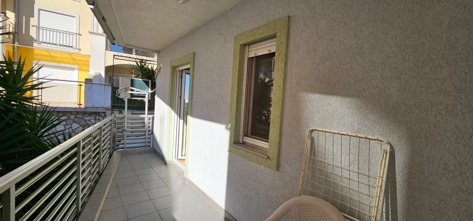 Spacious balcony with tiled flooring and railing.