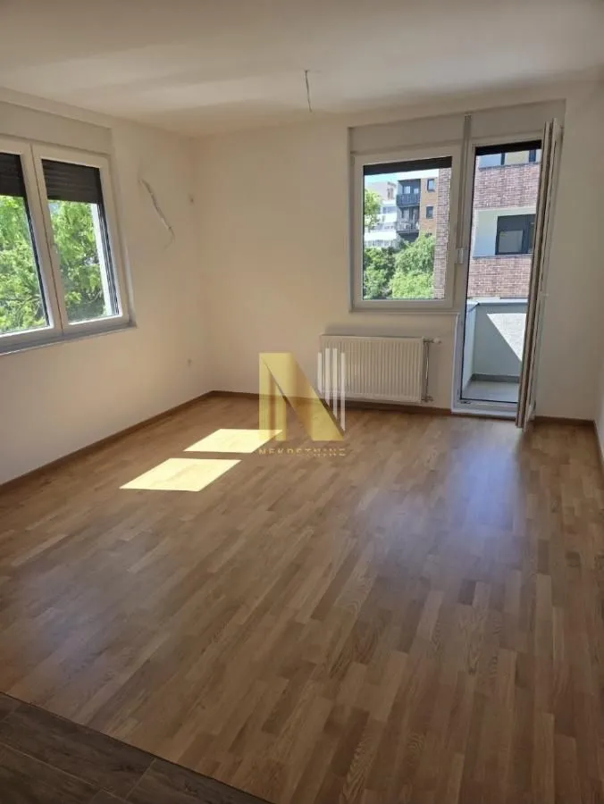 Prazna soba sa parketom i izlazom na terasu.