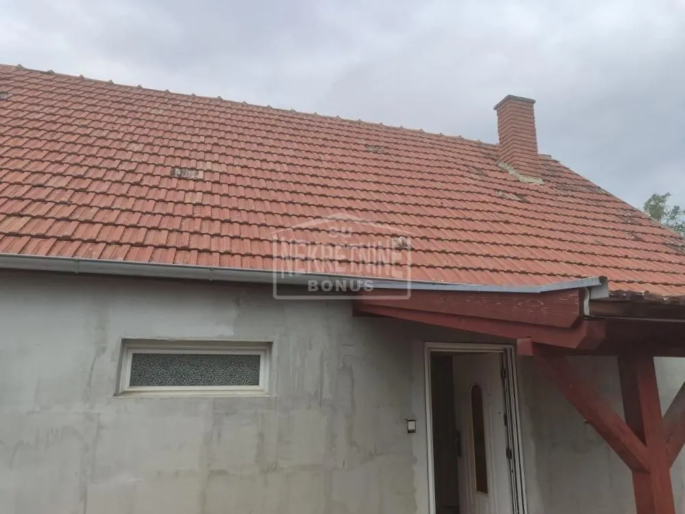 Pogled na spoljašnjost kuće sa krovom od crepa i ulaznim vratima.