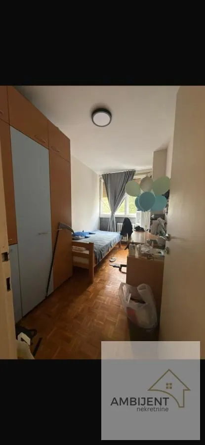Manja spavaća soba sa krevetom, radnim stolom i garderoberom.