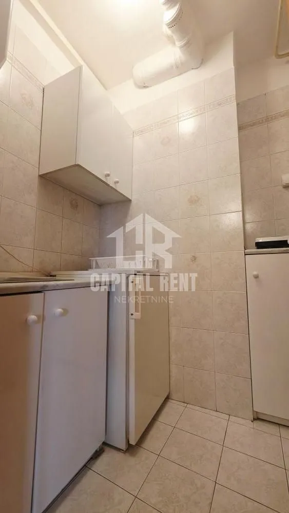 Small kitchen with white units and tiled walls.