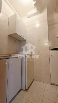 Small kitchen with white units and tiled walls. - image 7
