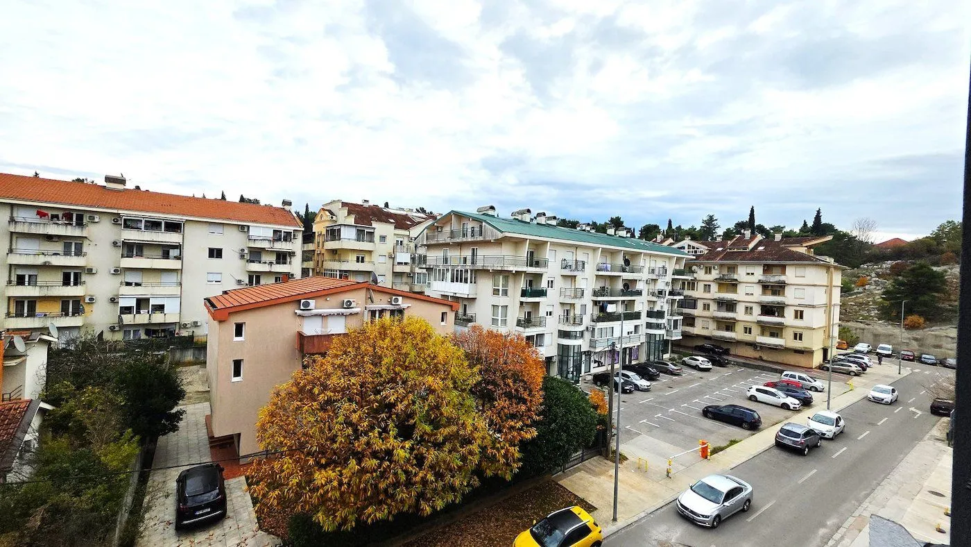 Pogled sa terase na okolne stambene zgrade i parking.