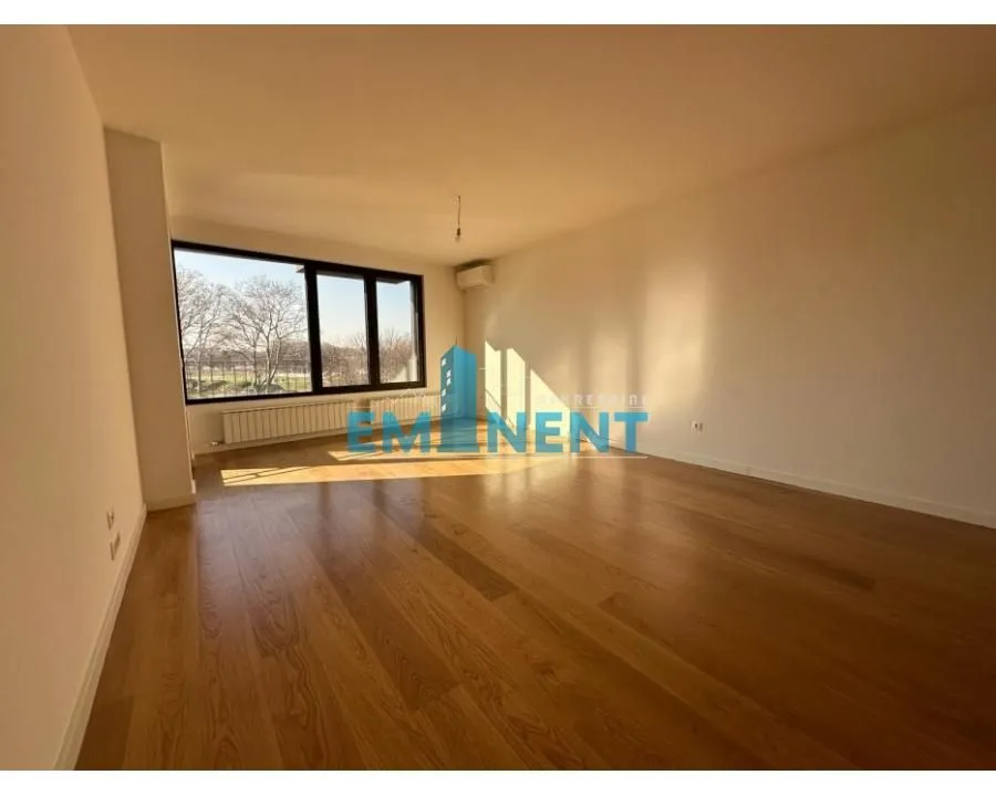 Empty room with wooden flooring and a large window.