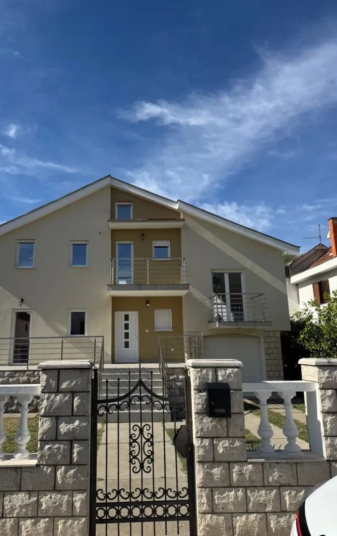 Front view of the house with an entrance door, fence, and balcony.