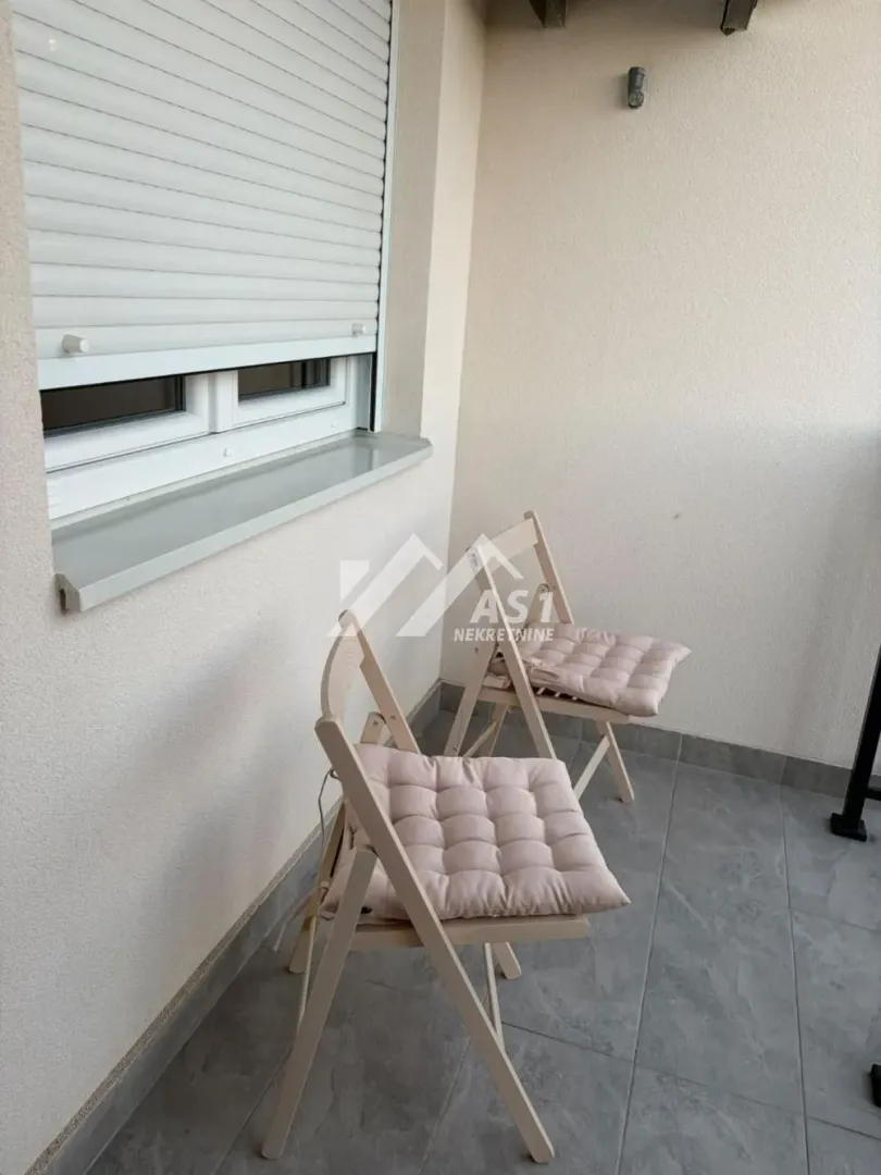 Manji balkon sa dve drvene stolice i jastucima za sedenje.