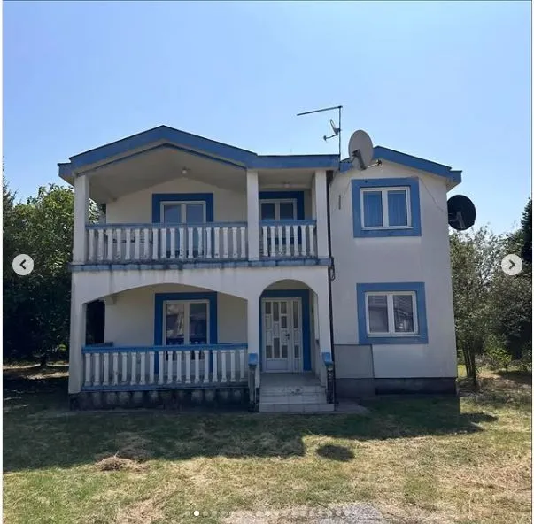 Dvospratna kuća sa plavim detaljima i dvorištem.