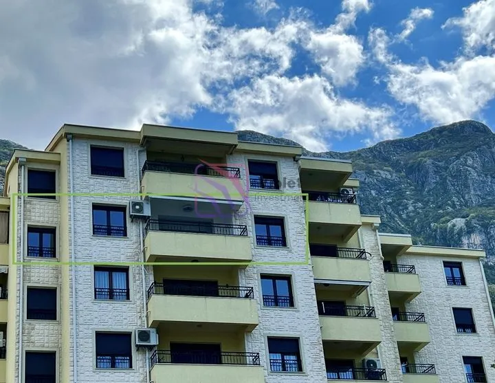 Pogled na spoljašnost stambene zgrade sa terasama i planinskim pejzažem u pozadini.