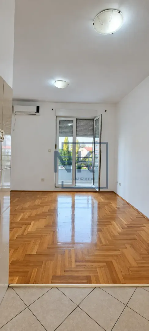 Prazna soba sa parketom i izlazom na terasu.