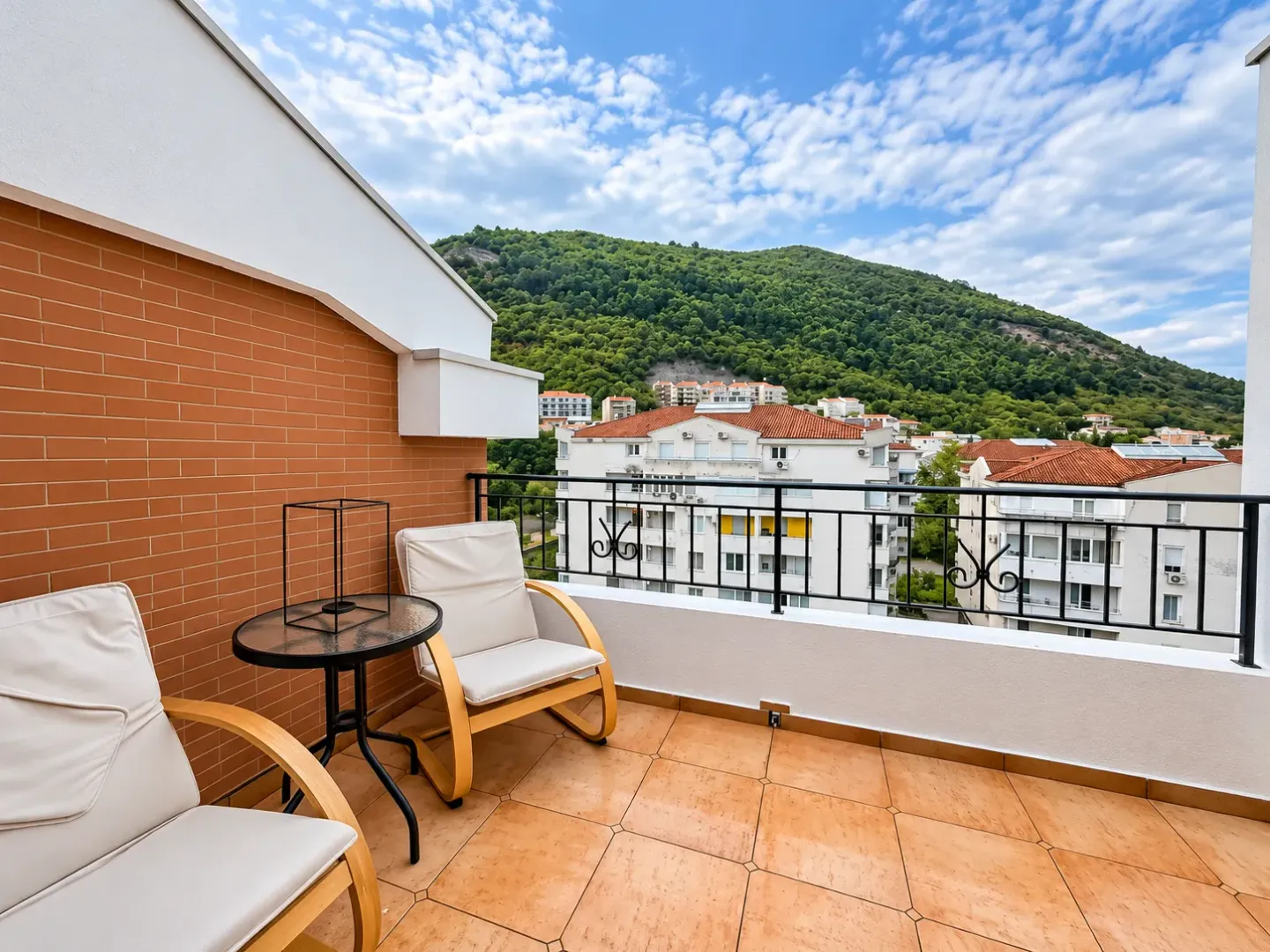 Namješten balkon sa garniturom za sjedenje i pogledom na brdo.
