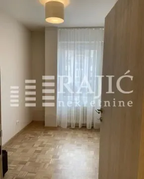 Empty room with parquet flooring and a window covered with a curtain. - image 2