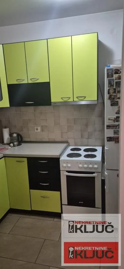 Manja kuhinja sa zelenim i crnim elementima i šporetom.