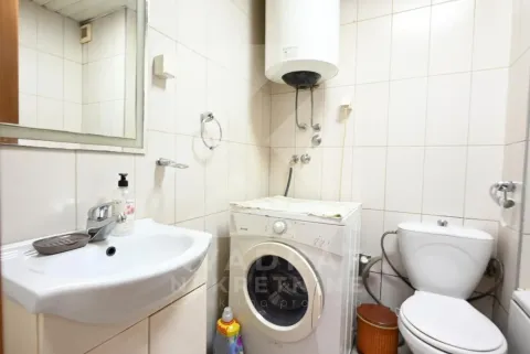 Bathroom with a sink, washing machine, and toilet. - image 12