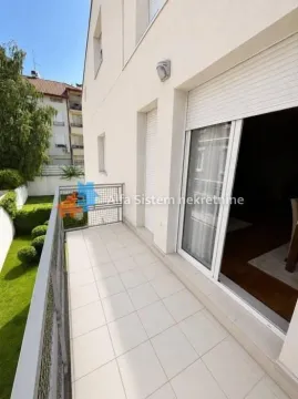 Prostrana popločana terasa sa pogledom na uređeno dvorište i okolne zgrade. - image 7