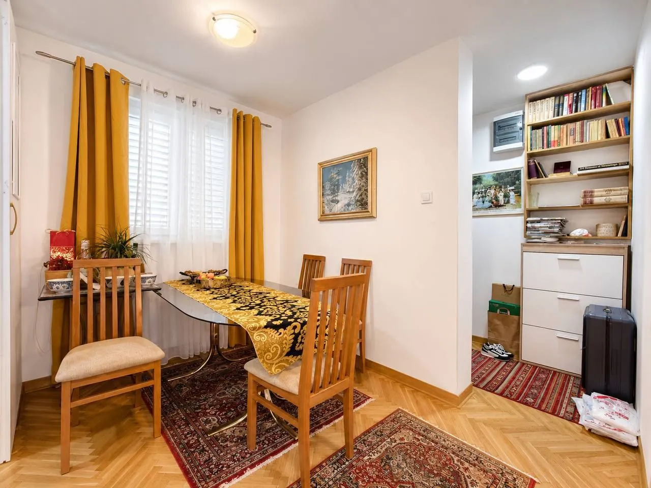 Dining area with a table, chairs, and a bookshelf.