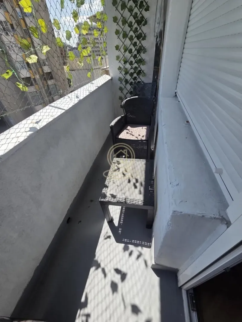 Manji namešteni balkon sa stolom i stolicama.