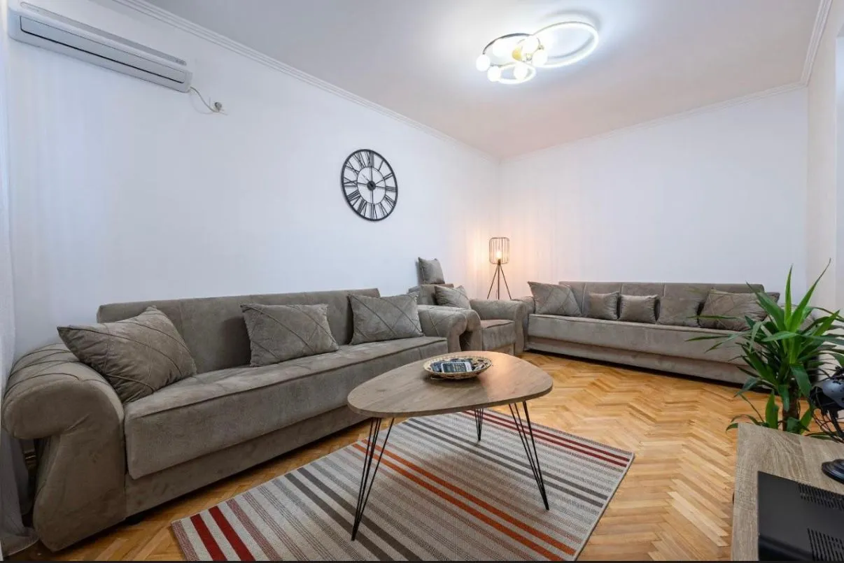Spacious living room with sofa set and parquet flooring.