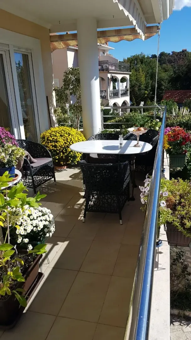 Prostrana terasa sa garniturom za sjedenje i ukrasnim biljem.