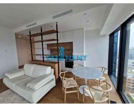 Living room with a sofa, dining table, and kitchen units. - image 4