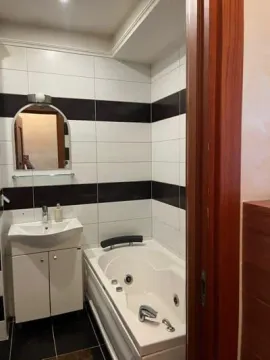 Small bathroom with a bathtub and washbasin, tiled in black and white. - image 7