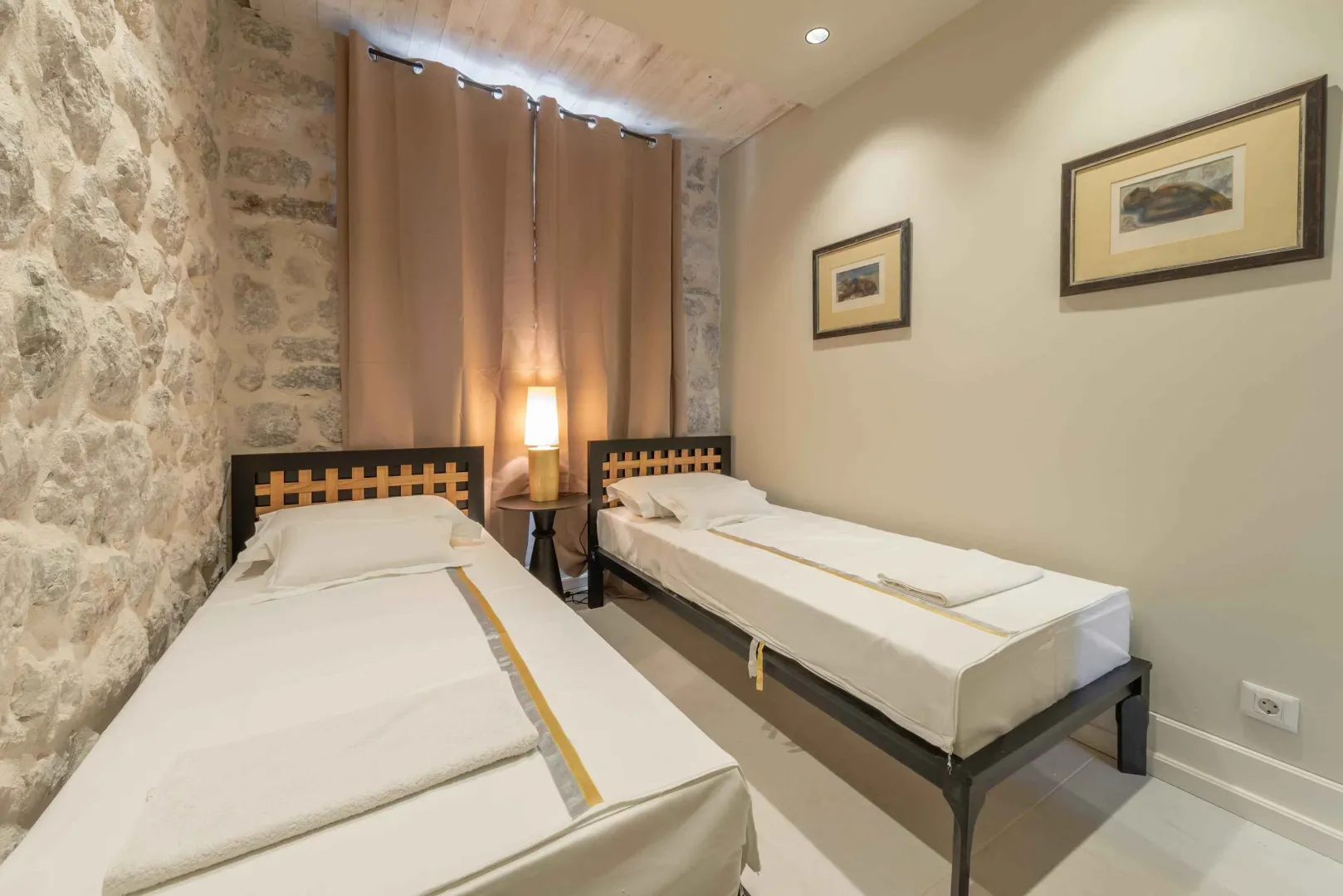 Bedroom with two single beds and an exposed stone wall.
