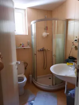 Small bathroom with a shower cabin, washbasin, and toilet. - image 8