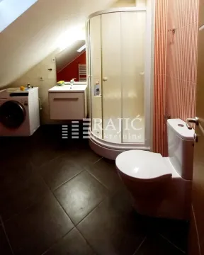 Attic bathroom with a shower cabin, sink, and washing machine. - image 8