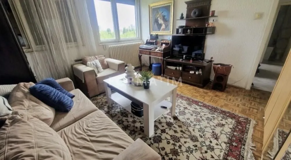 Namešten dnevni boravak sa garniturom, televizorom i trpezarijskim stolom.