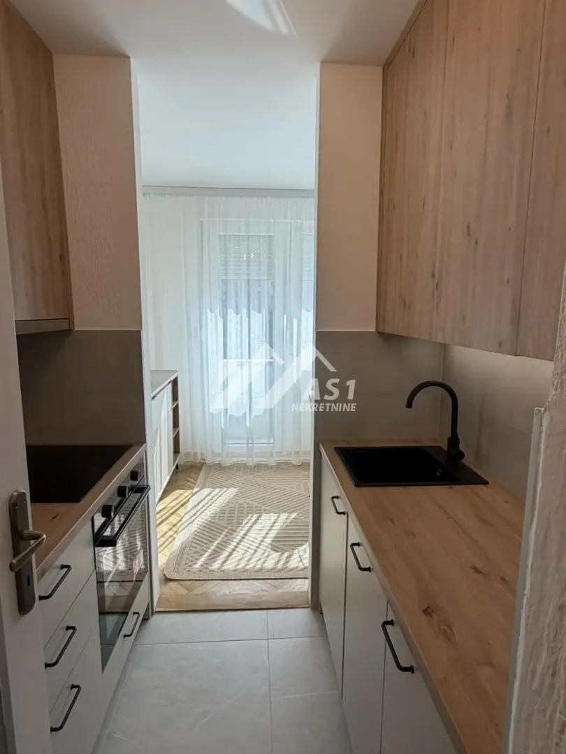 Manja kuhinja u prolazu sa drvenim radnim površinama i ugradnim elementima.