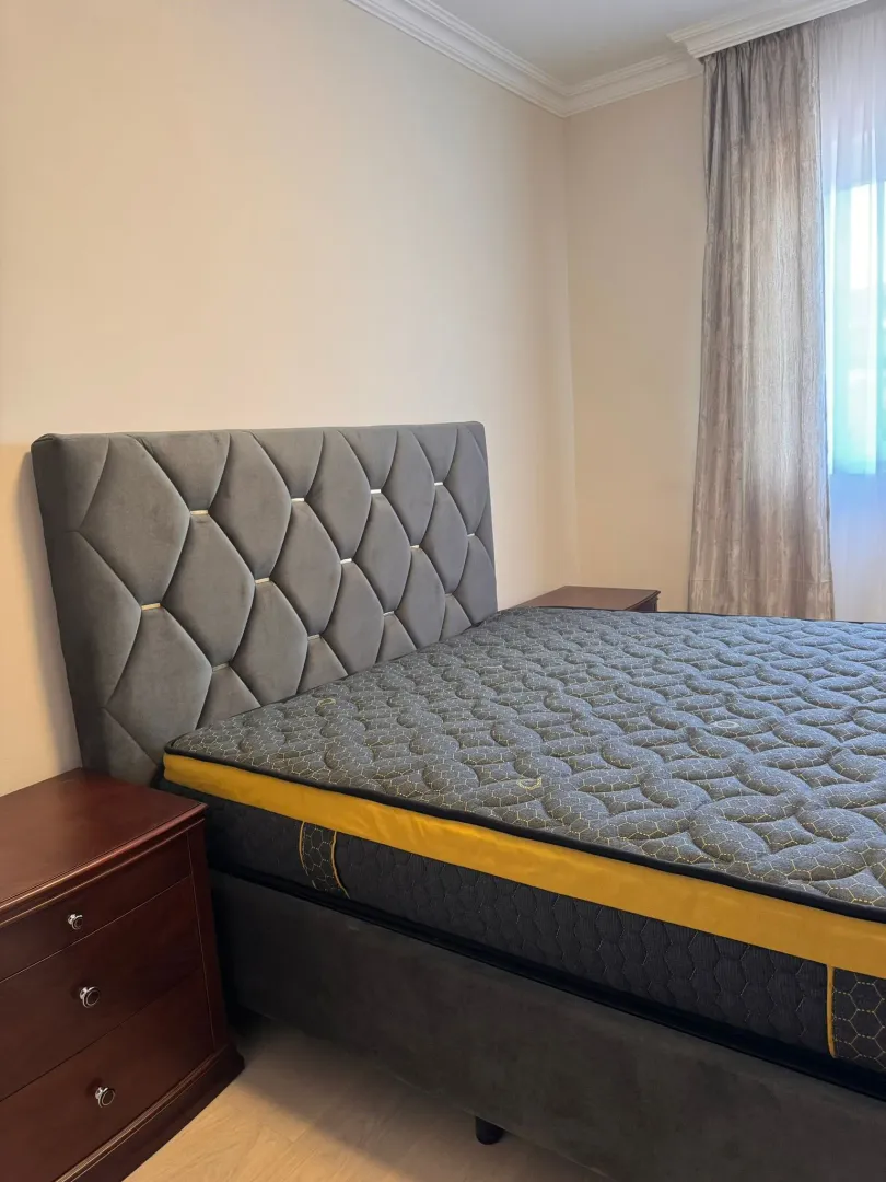 Double bed with a tufted headboard and bedside tables in the bedroom.