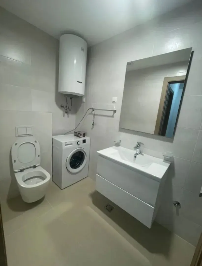 Modern bathroom with a sink, toilet, washing machine, and water heater.