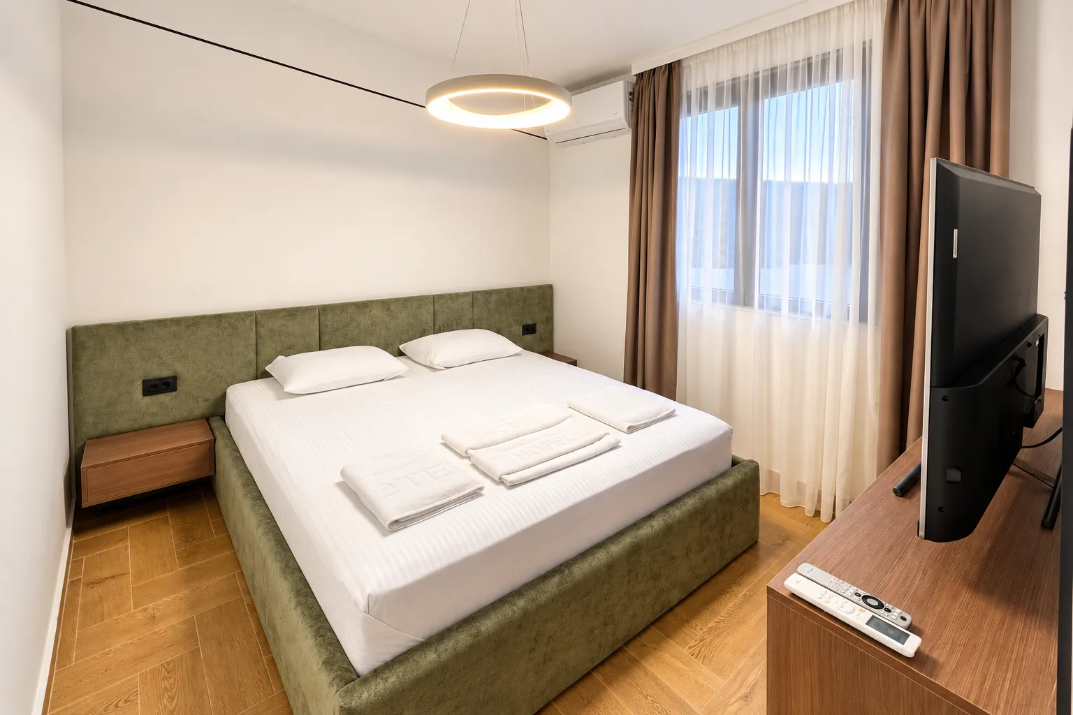 Furnished bedroom with a double bed, TV, and window.
