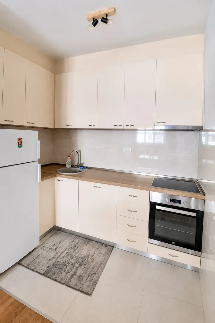 Small kitchen with light cabinetry, built-in oven, and refrigerator.