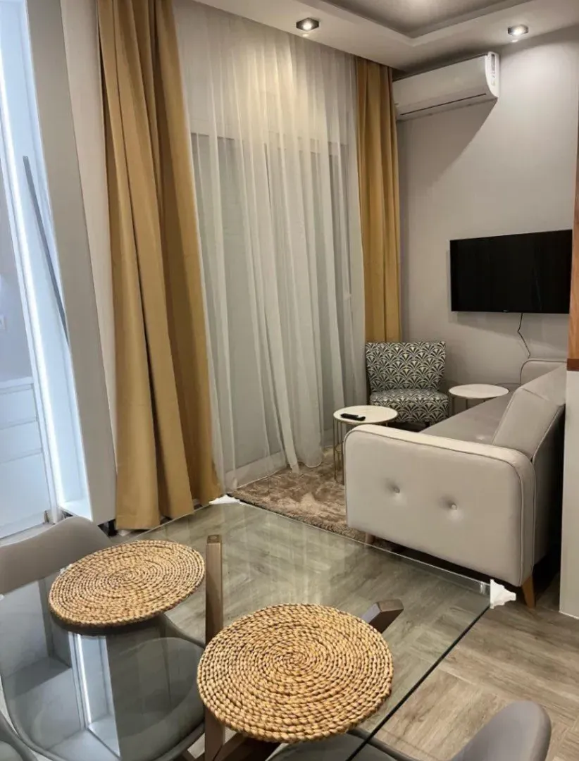 Modern living room with a sofa, TV, and dining table.