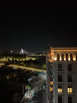 Noćni pogled na fasadu zgrade i osvijetljeni most u daljini. - image 9