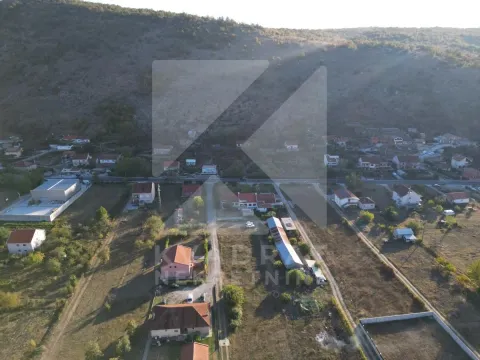 Pogled iz vazduha na naselje i okolni pejzaž sa brdom u pozadini. - image 2