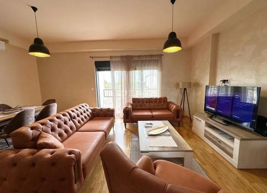 Spacious living room with brown leather seating furniture, dining area, and a TV.
