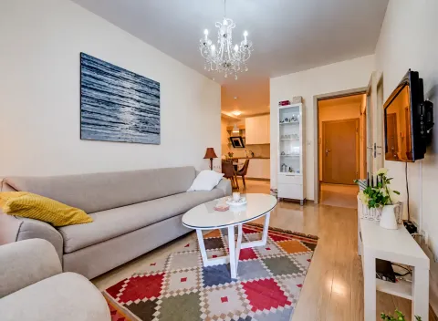 Dnevna soba sa garniturom, stočićem i televizorom na zidu. - image 2