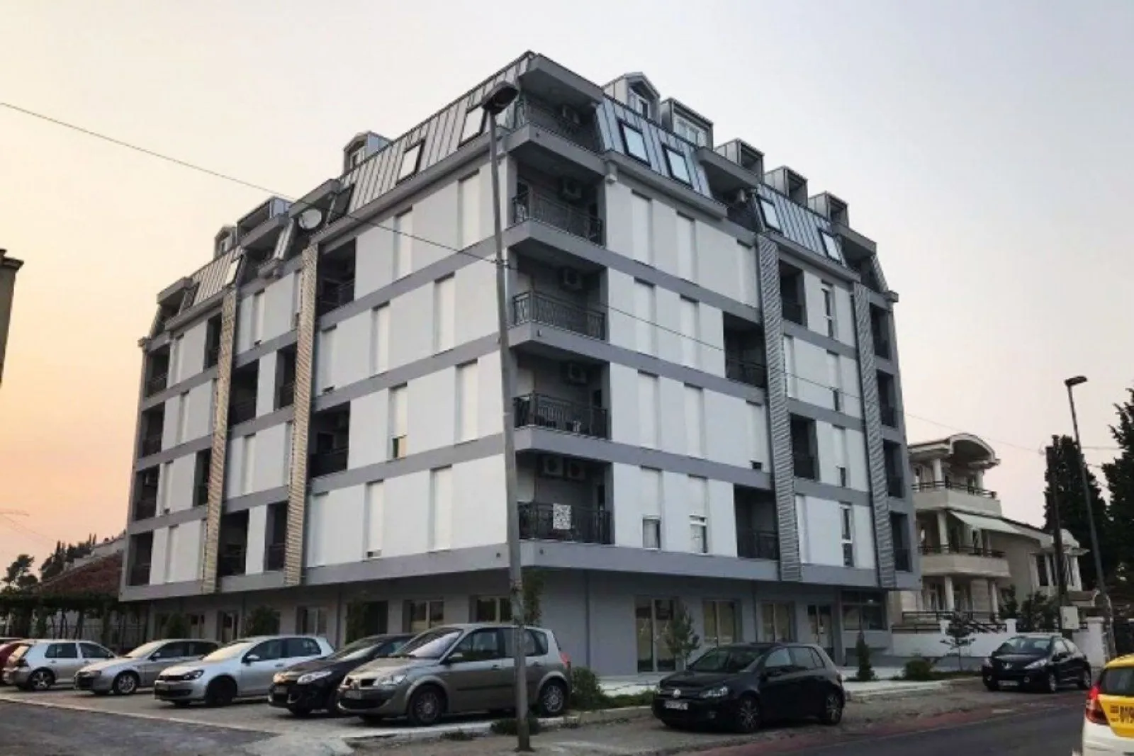Exterior of a modern residential building with parking spaces in front.