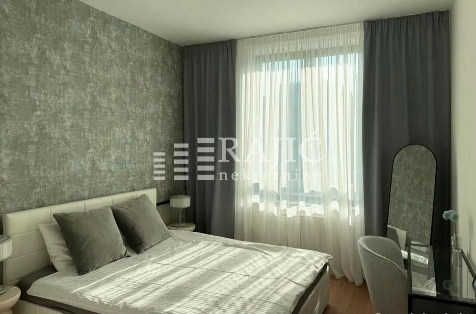 Furnished bedroom with a double bed and a window with dark curtains.
