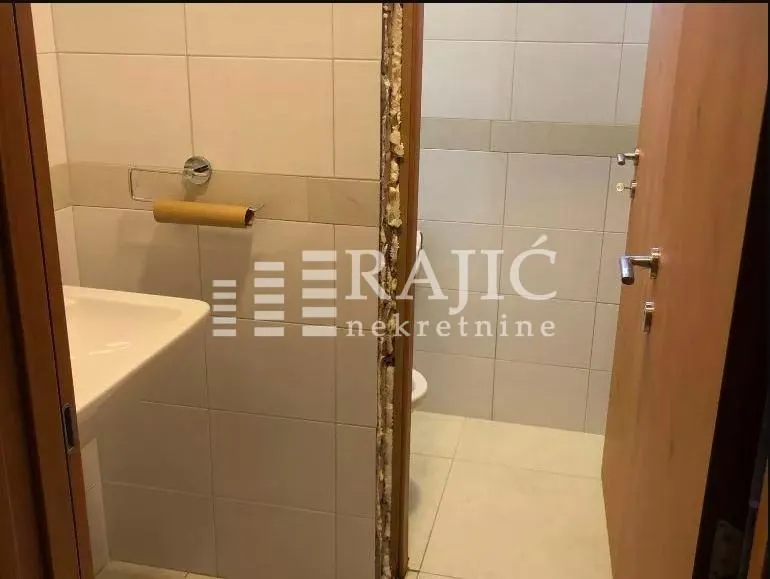 View of the bathroom with ceramic tiles and a washbasin.