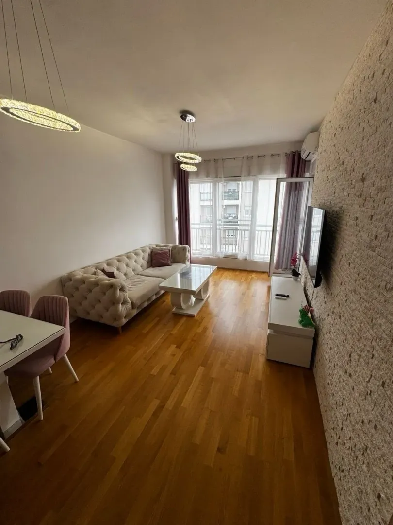 Living room with sofa, dining table, and TV unit.