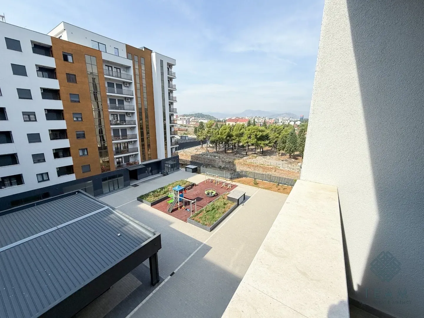 View from the balcony overlooking the residential building and courtyard with a children's playground.
