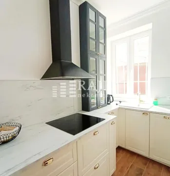 Modern kitchen with white cabinets, dark wall units, and a built-in cooktop. - image 9
