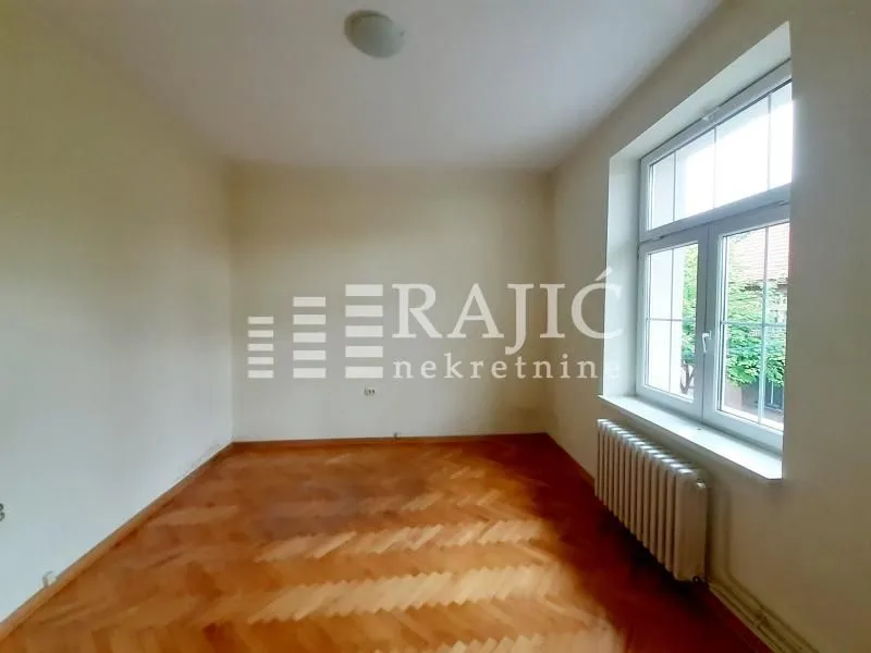 Empty room with parquet flooring and a window.