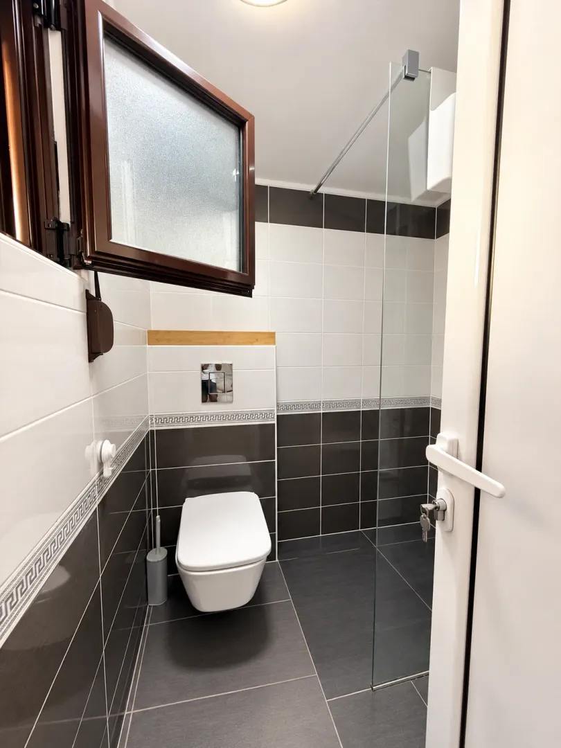 Moderne kupatilo sa tuš kabinom i ugradnim WC šoljom.