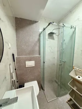 Modern bathroom with a glass shower enclosure, sink, and tiled walls. - image 7