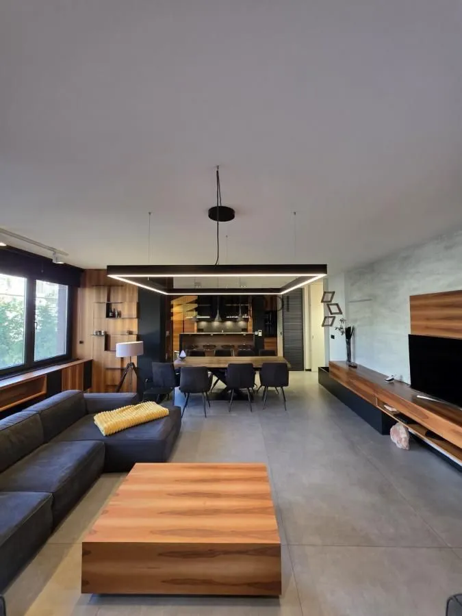 Prostrani dnevni boravak sa garniturom, trpezarijom i modernim osvetljenjem.